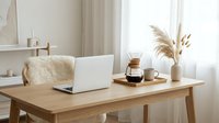 Minimalist Scandinavian home office with laptop, coffee maker, and pampas grass decor on wooden desk, bright cozy workspace interior.