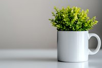 Fresh green artificial boxwood leaves arranged in white ceramic coffee mug on neutral background, minimalist home decor styling for modern interior design.