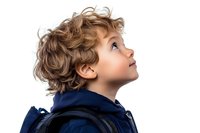 Young boy with curly brown hair wearing navy blue jacket looking up with wonder and curiosity, side profile portrait against white background.