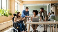 Diverse business team collaborating in modern office with wheelchair accessible workspace promoting inclusion and teamwork in corporate environment.