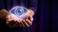 Hands holding glowing digital eye symbol with blue light effect against dark background, representing vision, technology, surveillance, and future innovation.
