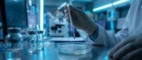 Scientist in laboratory conducting research with petri dishes and test tubes under blue lighting in modern facility.