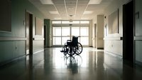 Empty wheelchair in hospital corridor with natural light from windows creating peaceful healthcare environment for medical rehabilitation.