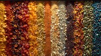 Vibrant rows of aromatic spices and seasonings arranged in colorful stripes, from deep red paprika to golden turmeric, creamy garlic, and blue peppercorns creating culinary palette.