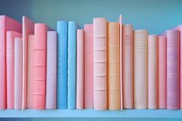 Colorful pastel books arranged in a row on blue shelf, featuring pink, blue, and orange spines creating a soft aesthetic for home decor or library display.