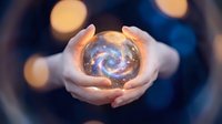 Hands holding glowing crystal ball with swirling galaxy inside against bokeh lights background for fortune telling mystical spiritual concepts.