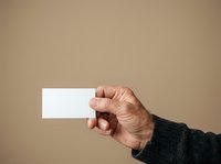 Mature man with light skin tone holding blank white card in hand against neutral beige background for business, marketing, or promotional use.