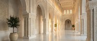 Elegant Islamic architecture corridor with ornate arches, detailed stone carvings, and warm golden lighting creating luxurious interior space for hospitality design.