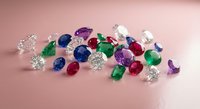 Collection of colorful precious gemstones including diamonds, emeralds, sapphires and rubies scattered on pink surface for jewelry making and luxury design.