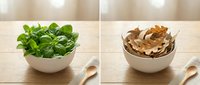Fresh green basil herb in white ceramic bowl with wooden spoon on wooden table surface, alongside dried basil leaves for cooking and culinary use.