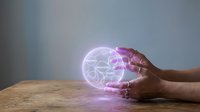 Hands holding glowing holographic sphere with interconnected network nodes on wooden surface representing digital connectivity and futuristic technology concepts.