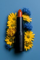 Red lipstick on blue background with yellow daisies and blue cornflowers creating natural cosmetic composition for beauty and makeup advertising.