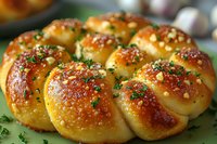 Freshly baked golden bread rolls arranged in circle, topped with garlic, herbs and coarse salt. Glossy brown crust with vibrant green parsley garnish creates appetizing appeal.