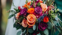 Vibrant wedding bouquet featuring coral, purple and pink roses mixed with eucalyptus leaves and delicate wildflowers against soft blurred background. For celebration decor.