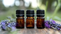 Three amber essential oil bottles arranged on wooden surface with fresh lavender flowers creating aromatherapy and wellness composition in natural light.