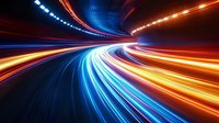 Abstract long exposure light trails in tunnel creating dynamic motion effect with vibrant blue and orange streaks against dark background, suggesting high-speed movement.