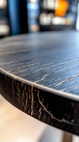 Close-up view of dark wooden table edge with distressed finish and natural grain pattern showing rustic texture and weathered surface detail. Suitable for interior design.