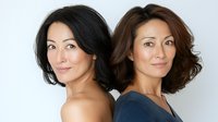 Asian women with natural makeup and confident expressions stand back to back, showcasing different hairstyles - straight black and wavy brown - against white background.