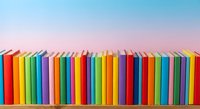 Colorful books arranged in row on shelf against gradient sky background. Library collection with rainbow spines for education and reading concepts.