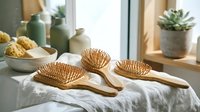 Natural bamboo hair brushes set on white linen with spa accessories and succulents in bright bathroom interior for wellness and self-care routine.
