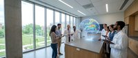 Medical professionals examining holographic Earth globe in modern hospital conference room with diverse healthcare team collaboration.
