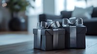 Elegant black gift boxes with silver satin ribbons and bows arranged on wooden table surface in moody lighting, creating luxurious festive atmosphere.