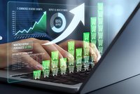 Business professional analyzing ecommerce growth data with digital interface showing rising sales charts and shopping cart icons on laptop screen.
