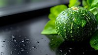 Fresh dark green round pumpkin with water drops and green leaves on black background, selective focus, macro photography for food and harvest concept.