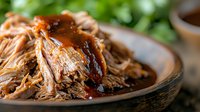 Tender slow-cooked pulled pork with rich barbecue sauce on rustic wooden plate, perfect for restaurant menus and food blogs.