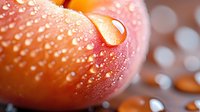 Fresh ripe tomato with water droplets in macro view showing natural texture and vibrant red-orange color against blurred background.