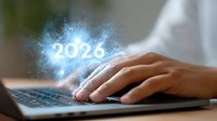 Glowing futuristic number 2026 emerging from laptop keyboard with hands typing, representing digital technology and future business planning concept.