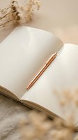 Open notebook with blank pages and rose gold pen, dried flowers nearby on neutral beige background. Perfect for journaling, planning, writing, and creative projects.