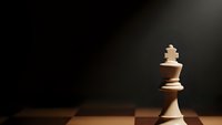 White chess king piece standing alone on wooden chessboard against dramatic dark background with spotlight illumination for strategy concepts.