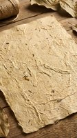 Handmade paper sheet with natural fiber texture on rustic wooden surface with twine and dried leaves for eco-friendly crafting and artistic projects.