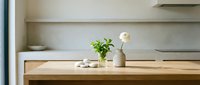 Modern minimalist kitchen counter with wooden surface, white ceramic vase, green plant and clean architectural details for contemporary home design.