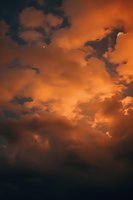 Dramatic orange storm clouds at sunset create moody atmospheric skyscape with dark undertones, suitable for nature and weather-themed designs.