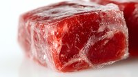 Fresh raw beef cube with marbling and frost crystals on white background, macro close-up shot showing meat texture and quality for food industry and culinary use.