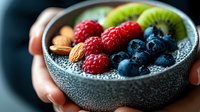 Fresh berries, kiwi and almonds in grey bowl with chia pudding. Healthy breakfast or dessert concept showing superfood ingredients and antioxidant rich foods.