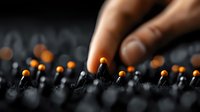 Hand lighting match from row of burnt matchsticks with glowing orange flames against dark background creating dramatic fire concept for restart and ignition.