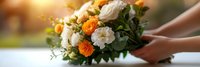 Hands holding fresh flower bouquet with white and orange blooms in warm sunlight for wedding celebration or romantic gift giving occasion.
