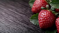 Fresh ripe strawberries with green leaves on dark wooden background. Macro shot with selective focus and copy space for food photography.