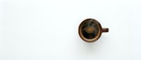 Brown ceramic coffee cup with black coffee viewed from above on white background for minimalist cafe branding and morning beverage concepts.