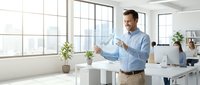 Caucasian male professional in business casual attire presenting data visualization in modern office with large windows and natural light, suitable for corporate training and business concepts.