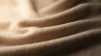 Soft beige wool fabric with natural texture and gentle folds, suitable for fashion design, textile backgrounds, and material mockups.