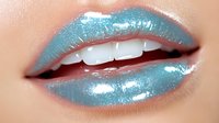 Glossy metallic turquoise lips with white teeth showing through parted mouth, featuring high-shine finish and professional makeup artistry for beauty and cosmetic concepts.