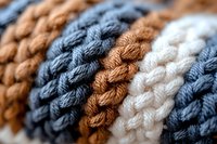 Close up macro shot of knitted wool texture in brown, navy blue and white colors showing detailed yarn pattern and soft textile structure. Suitable for craft backgrounds.