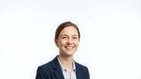 Professional businesswoman in navy suit smiling confidently against white background, corporate headshot for marketing materials and presentations.