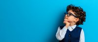 Young Hispanic boy wearing glasses and formal vest with thoughtful expression looking up against bright blue background, contemplative child portrait.