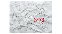Crumpled white paper covered with handwritten sorry words, one in red standing out, conveying apology, regret, and emotional concept.