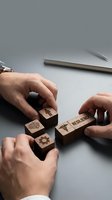Business hands arranging wooden blocks with resilience icons and symbols on modern office desk representing strategic planning and problem-solving skills.